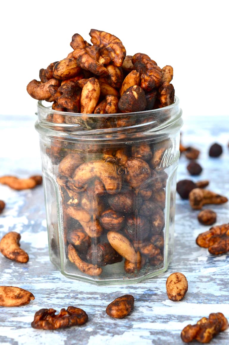 A jar with healthy roasted nuts spilling out of the top.