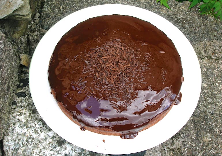 A glazed vegan spicy dark chocolate cake on a white plate.