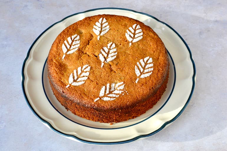 A round apple and thyme cake on a serving plate.