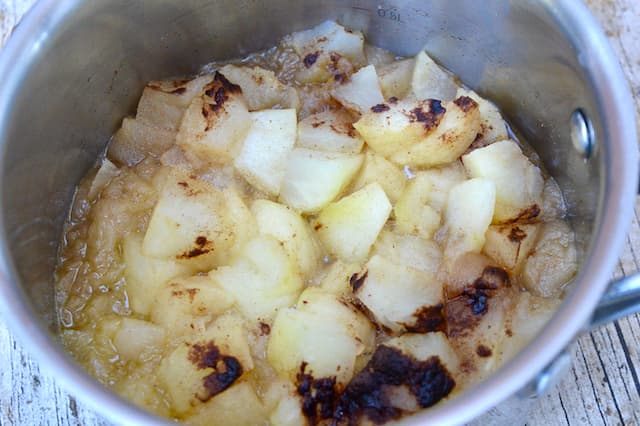 Cooked apples with cinnamon in a small saucepan.