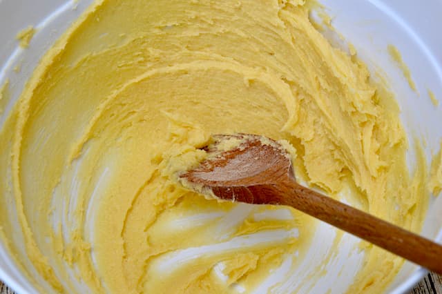 Creamed butter and sugar in bowl with wooden spoon.