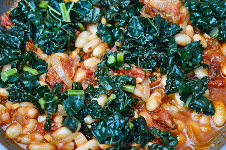Close up of cavolo nero kale with white beans, tomatoes and onions.