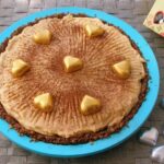 A no-bake chocolate cashew pie decorated with gold hearts in a turquoise silicone flan dish.