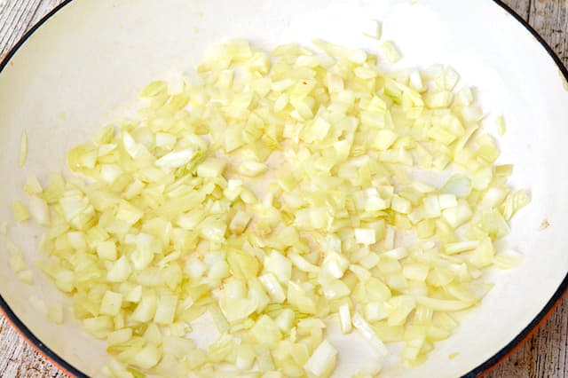 Finely chopped onions frying in a ceramic pan.