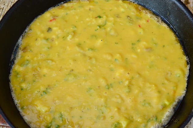Egg batter cooking in a cast iron skillet.