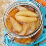 An open clip-top jar of pears poached in dessert wine.