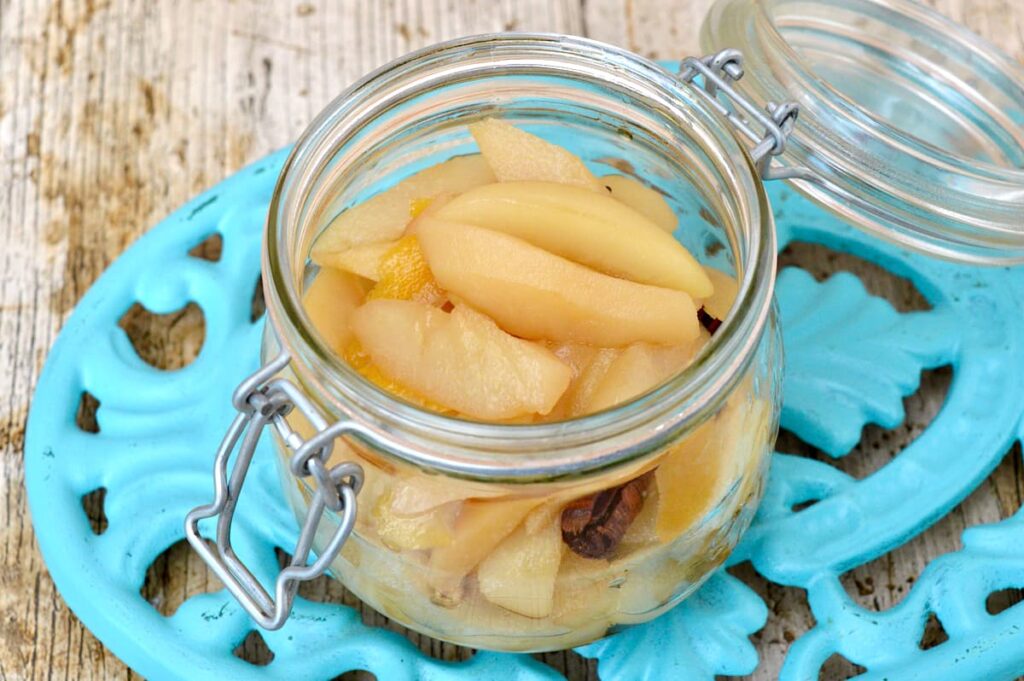 An open clip-top jar of pears poached in dessert wine before the poaching syrup is added.