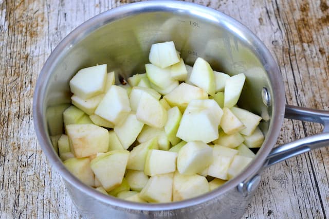 Peeled, cored and chopped cooking apples in a saucepan.