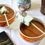 Two mugs of vegan hot chocolate with marshmallows. Ingredients also in image.