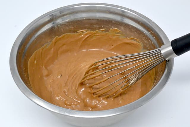 Castagnaccio batter in a mixing bowl with whisk.