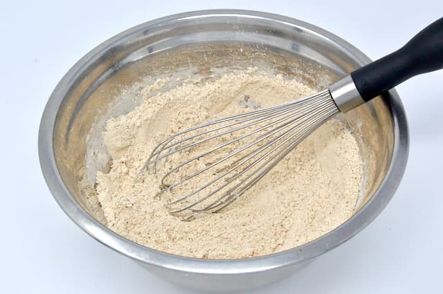 A mixing bowl of chestnut flour with whisk.