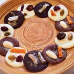 A bamboo platter of white, milk and dark chocolate sparkling mendiants.