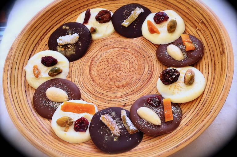 A bamboo platter of white, milk and dark chocolate sparkling mendiants.