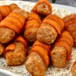A stack of vegan pigs in blankets on a patterned platter.