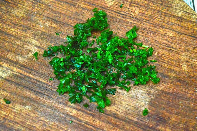 Finely chopped parsley on a chopping board.