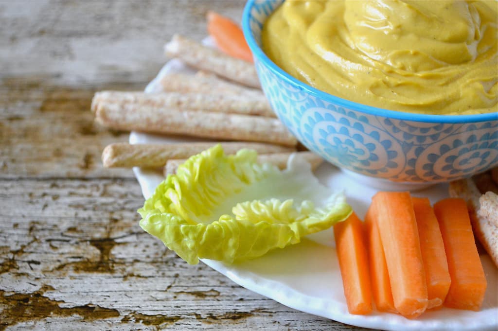 Vegan cheese dip in a bowl with breadsticks and crudités.