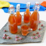 A glass and bottles of raspberry kombucha in post on How to Make Kombucha.