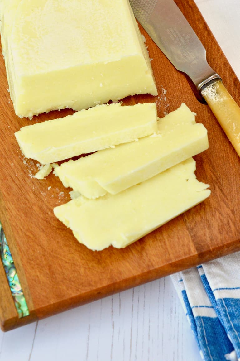Three slices of homemade vegan butter on a board with knife.