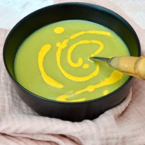 A bowl of homemade pea and leek soup with a drizzle of turmeric tahini sauce on top.
