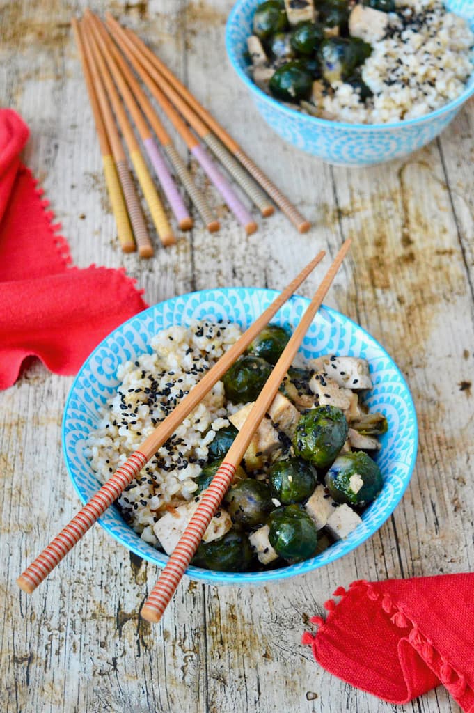 Two teriyaki rice bowls with tofu, Brussels sprouts and chopsticks.