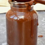 Easy vegan chocolate sauce made with champagne. Sauce covered spoon on top of pot.