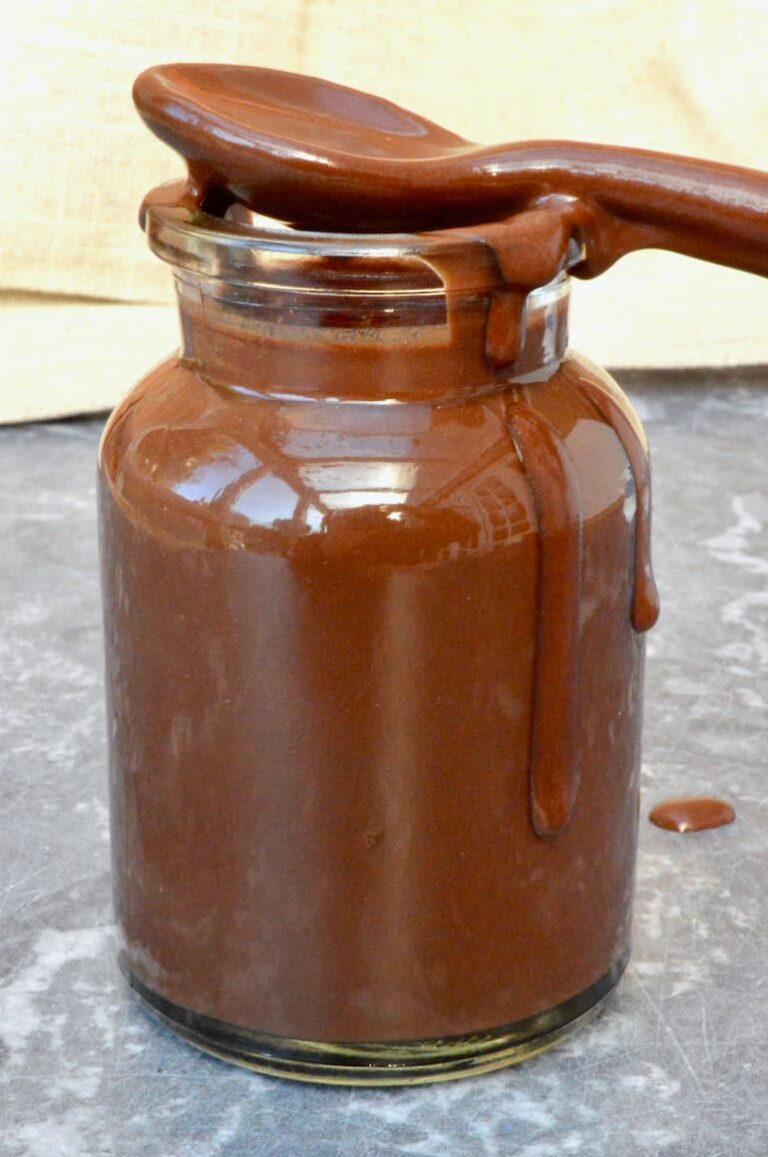 Easy vegan chocolate sauce made with champagne. Sauce covered spoon on top of pot.