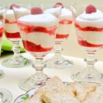 Glasses of layered raspberry syllabub with a plate of Chardonnay vanilla biscuits.