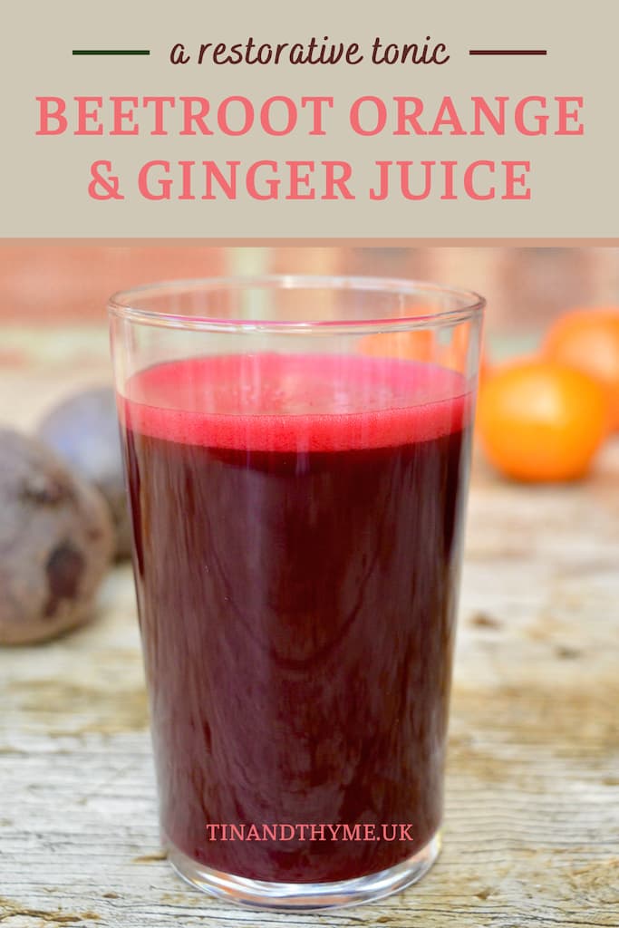 A glass of beetroot juice with orange and ginger. Whole beetroot and oranges in the background.
