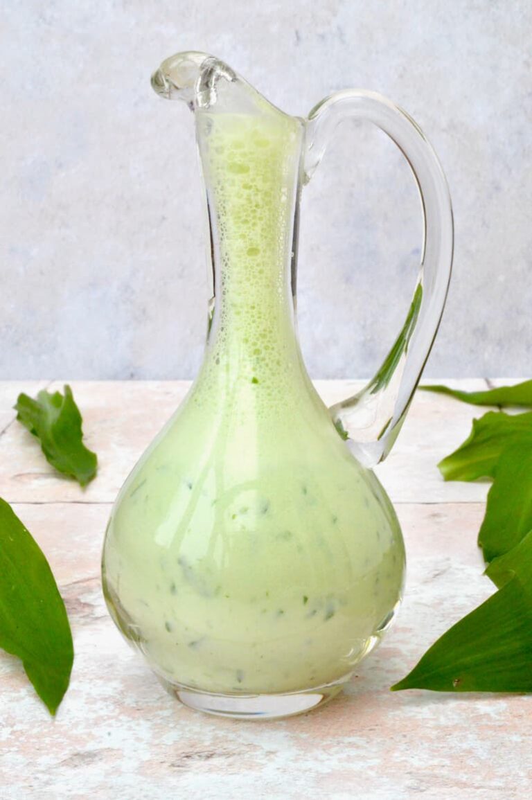 A glass salad oil jug filled with creamy wild garlic dressing.