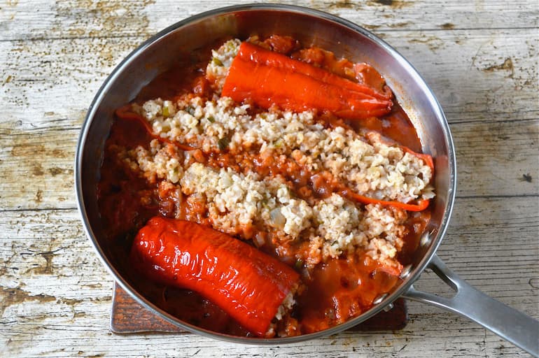 A pan of Syrian stuffed red peppers in tomato sauce (koosa mahshi).