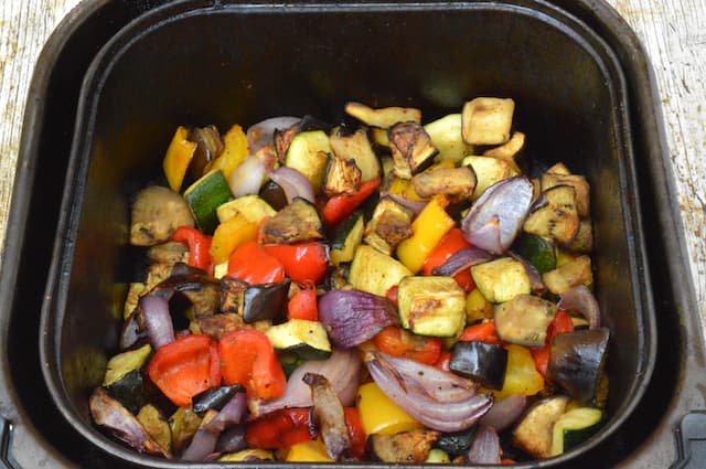 An air fryer drawer filled with roasted Mediterranean vegetables.
