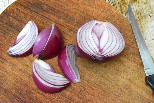 A red onion being cut into wedges.