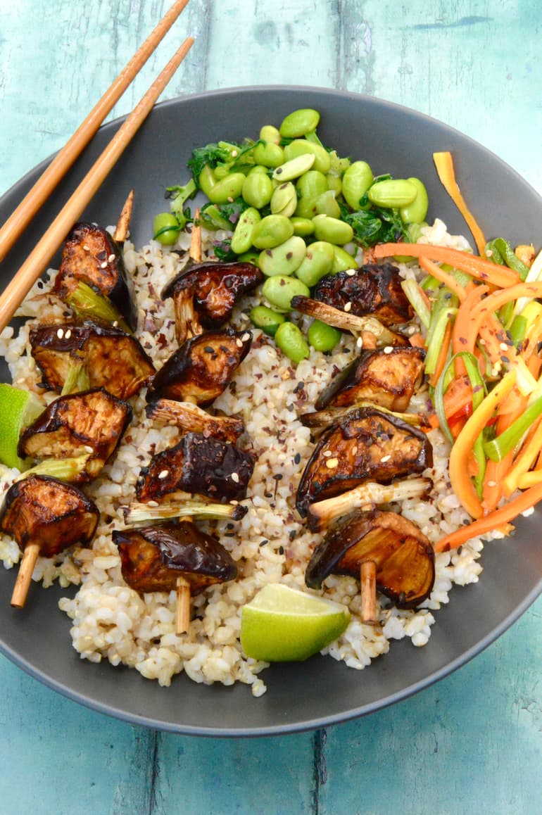 3 aubergine yakitori on a bed of short grain brown rice with edamame beans and carrot salad.