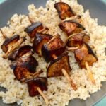 Vegetarian aubergine yakitori skewers atop a bed of short grain brown rice.