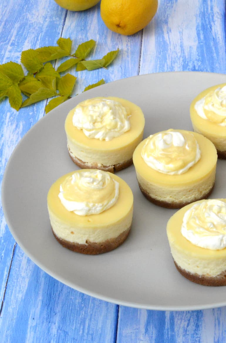 Partial view of a grey plate of mini baked lemon curd cheesecakes.