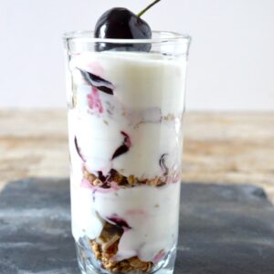 Cherry granola pot in a glass with a cherry on top.