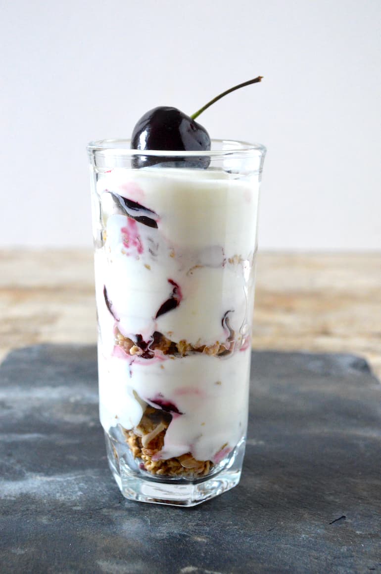 Cherry granola pot in a glass with a cherry on top.