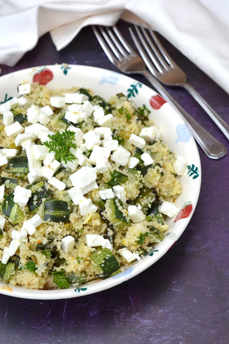 A bowl of herbed courgette (zucchini) couscous with feta scattered on top.