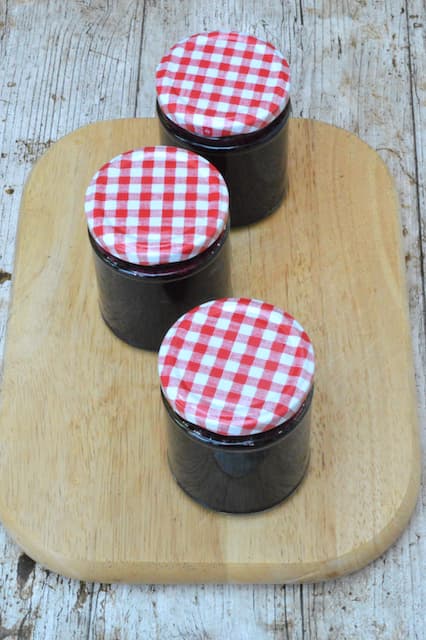 Three jars of homemade preserve with lids on.