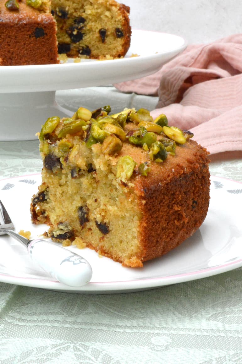A slice of dried apricot and almond cake with a sticky pistachio topping.
