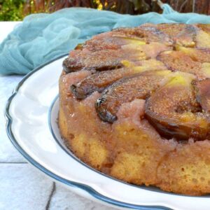 Partial view of an upside-down fig cake on a plate in the garden.