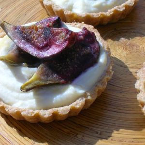 Roasted fig tarts with mascarpone white chocolate filling on a bamboo platter.