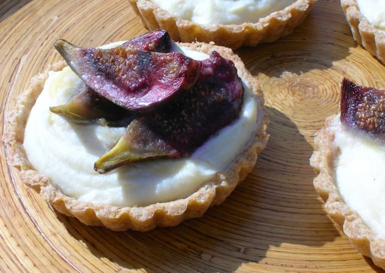Roasted fig tarts with mascarpone white chocolate filling on a bamboo platter.