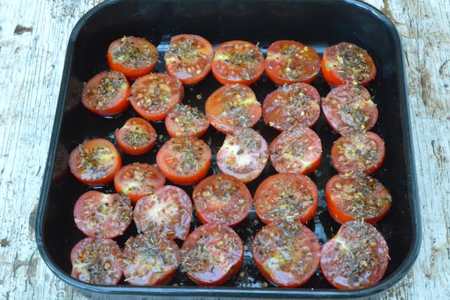Seasoned halved tomatoes in a roasting tin.