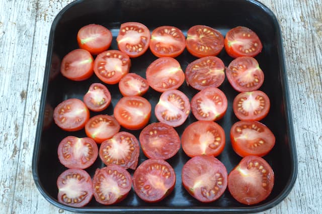 Halved tomatoes in a roasting tin.