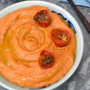 A bowl of roasted tomato and white bean dip with roasted tomatoes adorning the top.