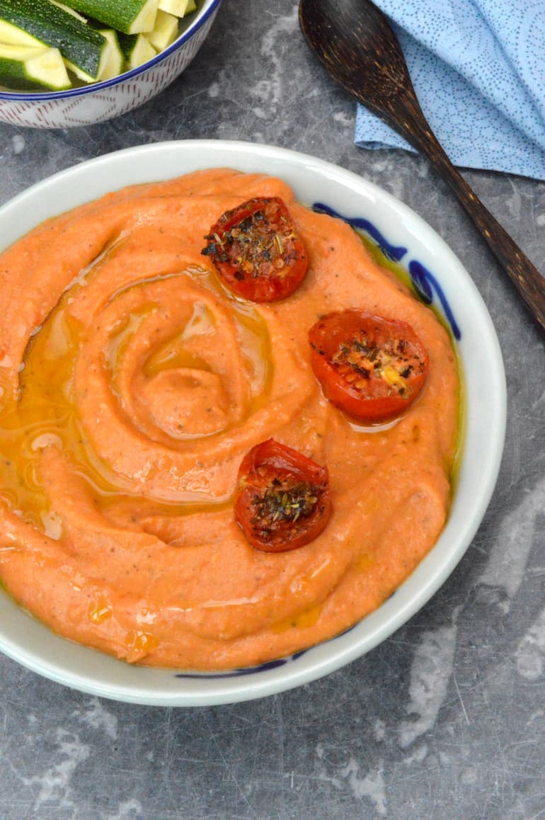 A bowl of roasted tomato and white bean dip with roasted tomatoes adorning the top.