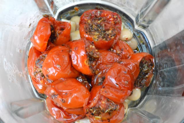 Cooked tomatoes and other ingredients in a blender jug.