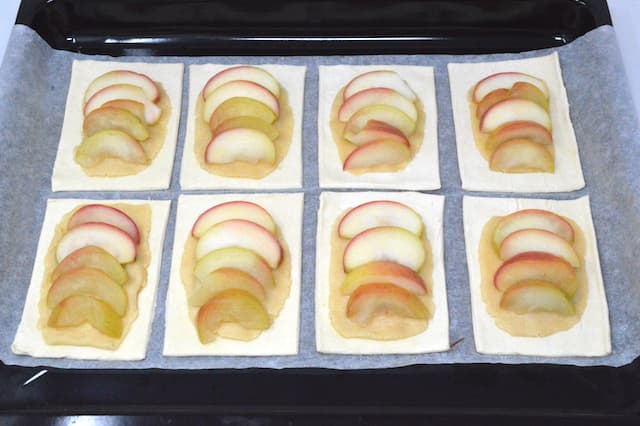 Poached apple slices on raw pastry rectangles.