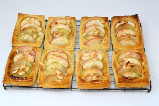Eight apple and almond pastries on cooling rack.